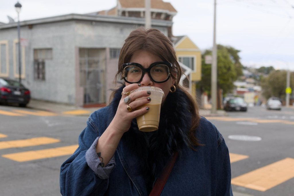Erin Nederbo, social media programs and systems strategist, sipping an iced coffee on a street corner